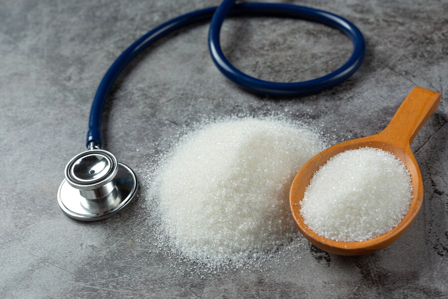 sugar in wooden bowl and stethoscope on dark background