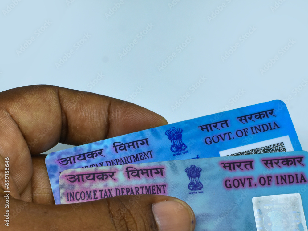 PAN identification ID card of India held in hand on white background. PAN Card is allotted to tax payers by Income Tax Department of India.